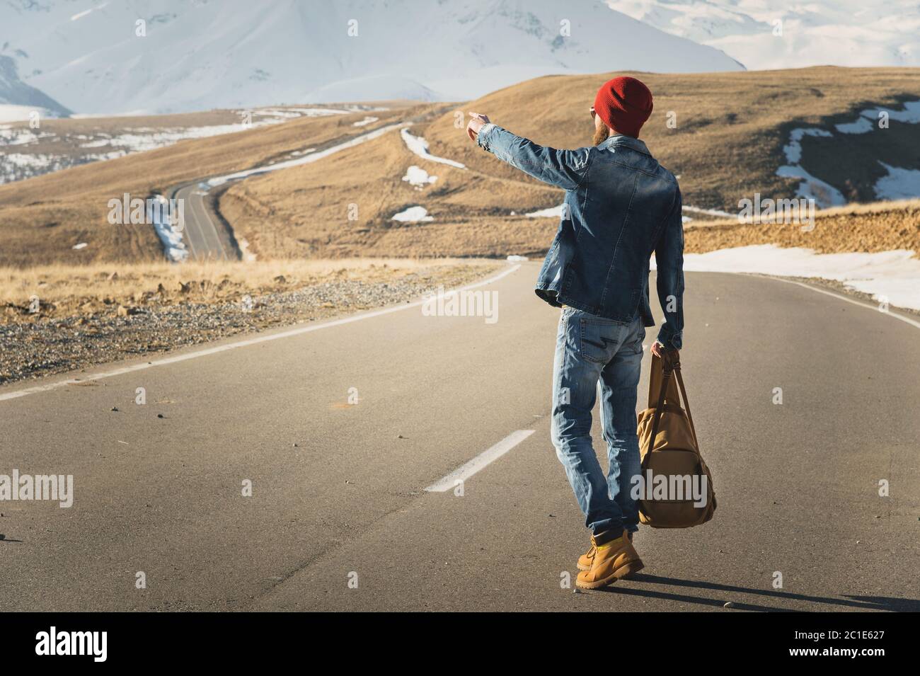 Concetto di turismo e di gente - Hipster elegante che cammina lungo la strada di campagna all'aperto e punta il dito a qualcosa Foto Stock
