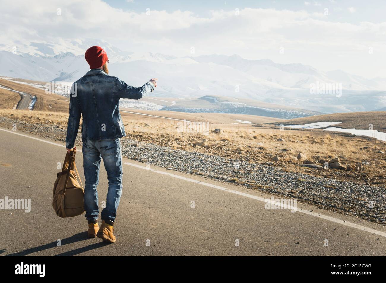 Concetto di turismo e di gente - Hipster elegante che cammina lungo la strada di campagna all'aperto e punta il dito a qualcosa Foto Stock