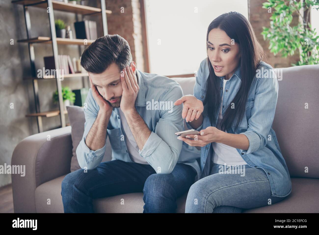 Foto di due persone frustrata donna uso smartphone ricerca sms trovare un'altra donna messaggio punta mano scioccato uomo seduta comfort comodo divano stanco Foto Stock