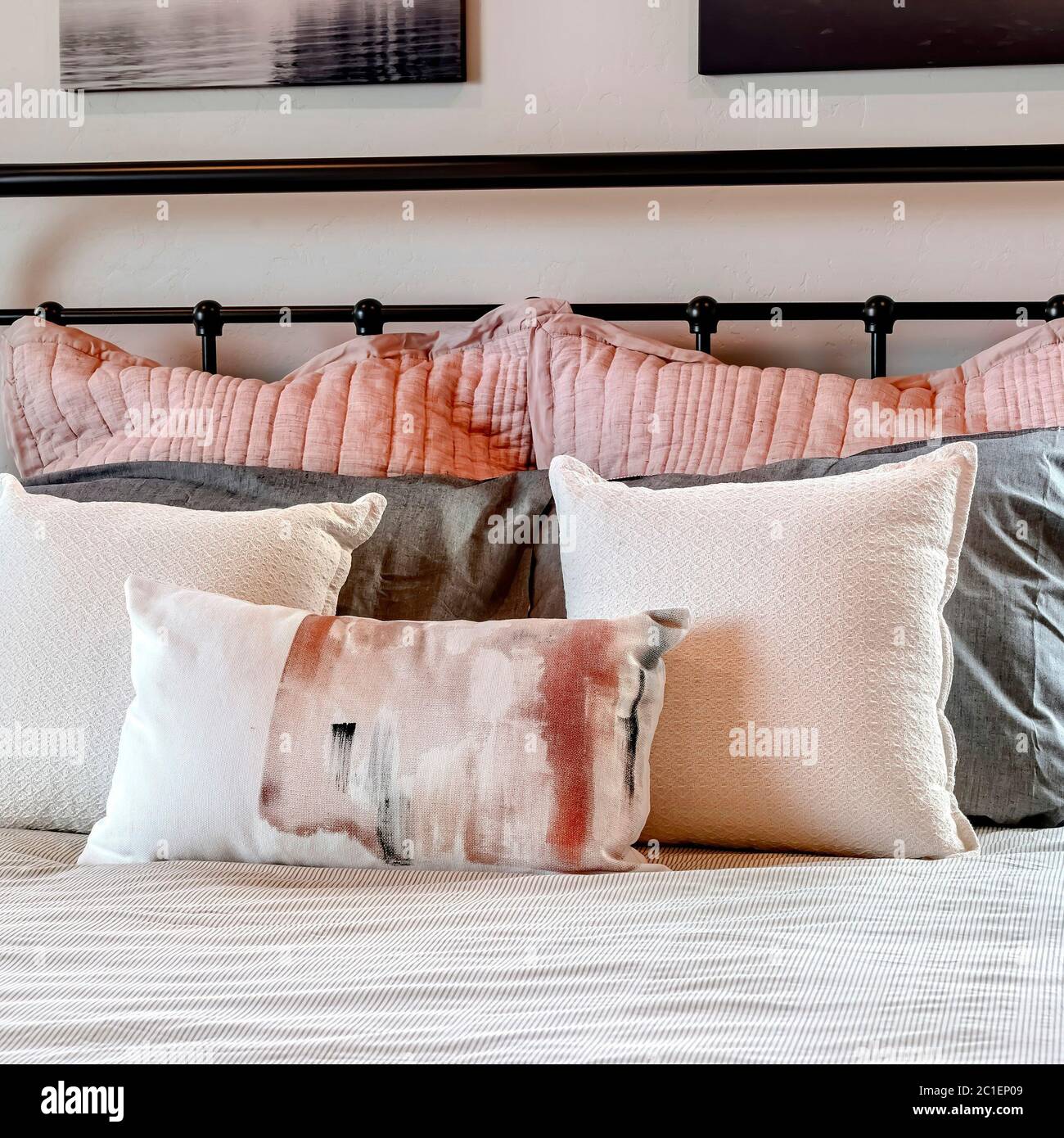 Letto singolo quadrato con morbidi cuscini contro la testiera in metallo  nero all'interno della camera da letto Foto stock - Alamy