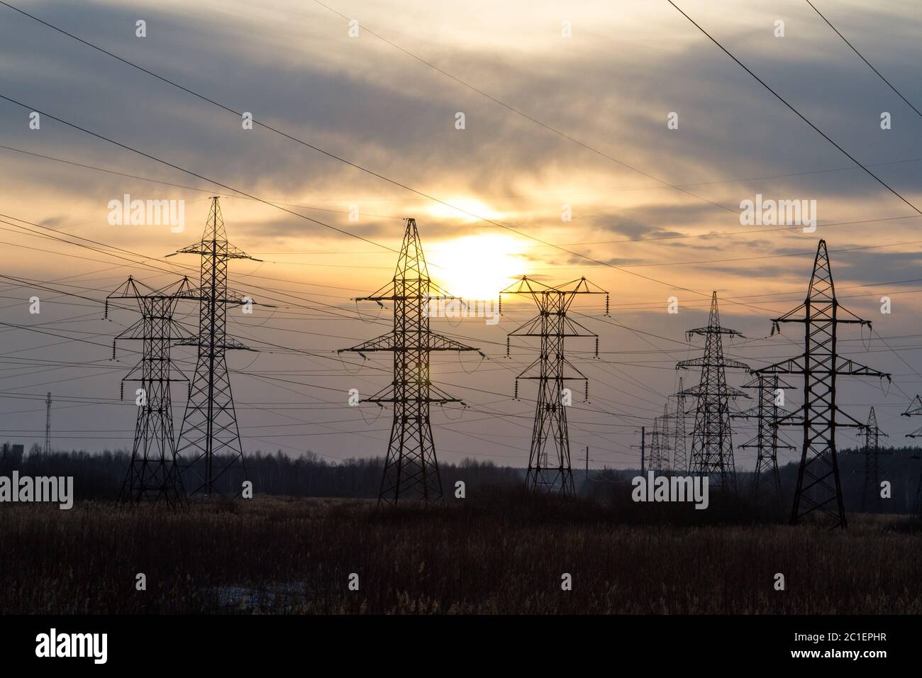 Linee di alimentazione ad alta tensione al centro di un campo al tramonto. Industrializzazione. Elettrificazione. Alimentazione. Foto Stock