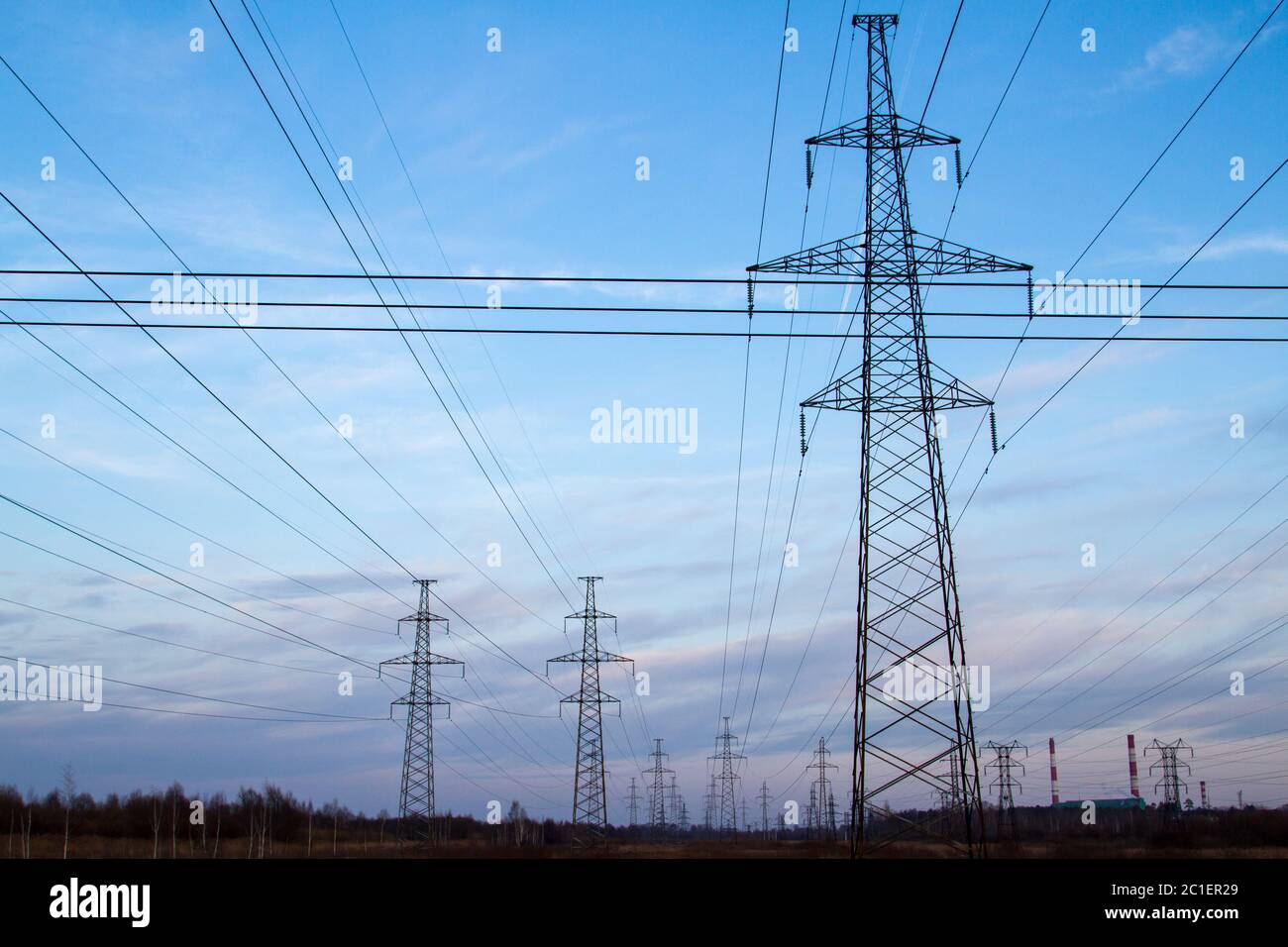 Linee di alimentazione ad alta tensione al centro di un campo al tramonto. Industrializzazione. Elettrificazione. Alimentazione. Foto Stock