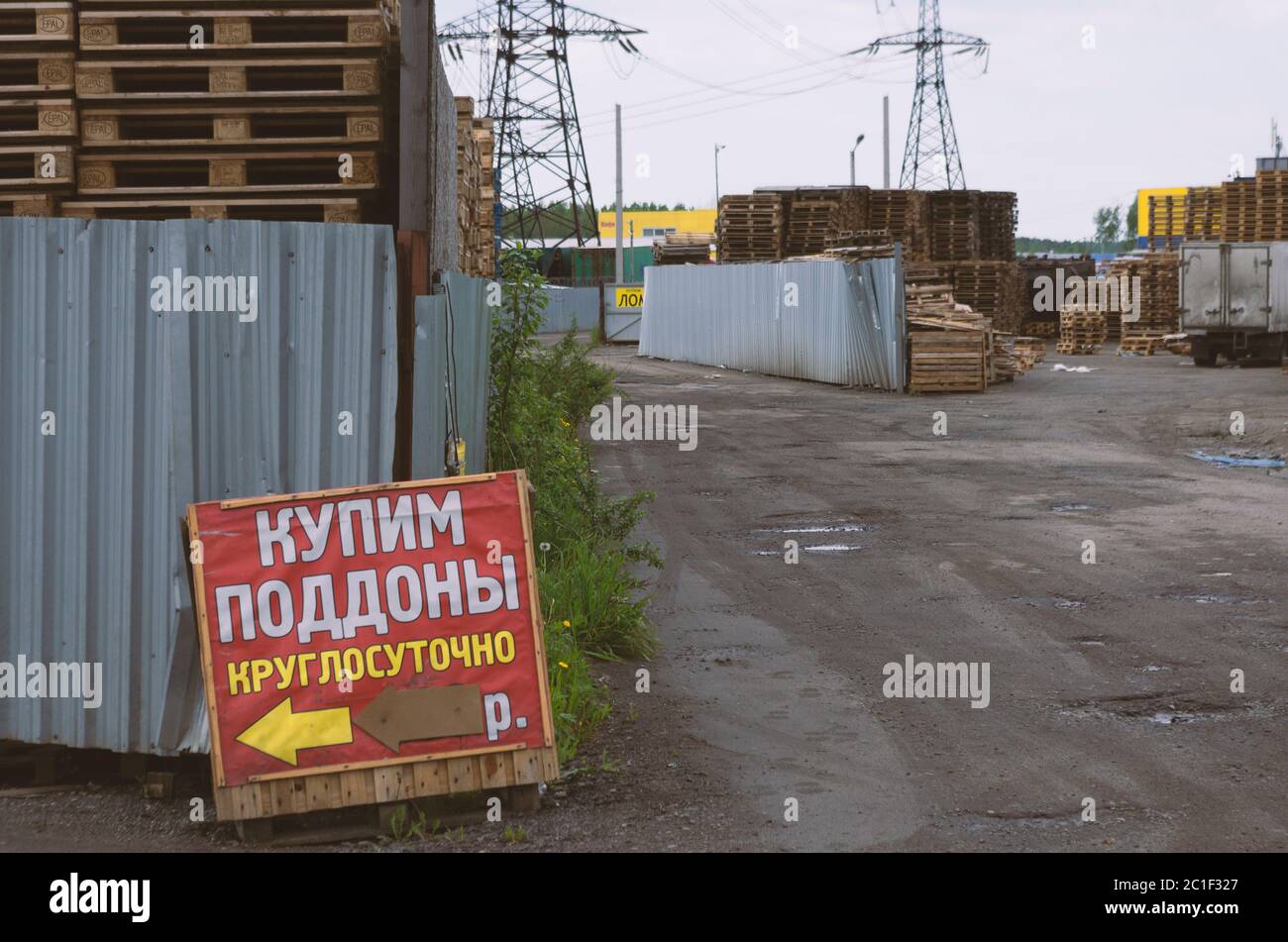 San Pietroburgo, Russia - 7 giugno 2020: File di pallet dietro la recinzione e manifesti con l'iscrizione in russo 'acquistare pallet 24 ore su 24 Foto Stock