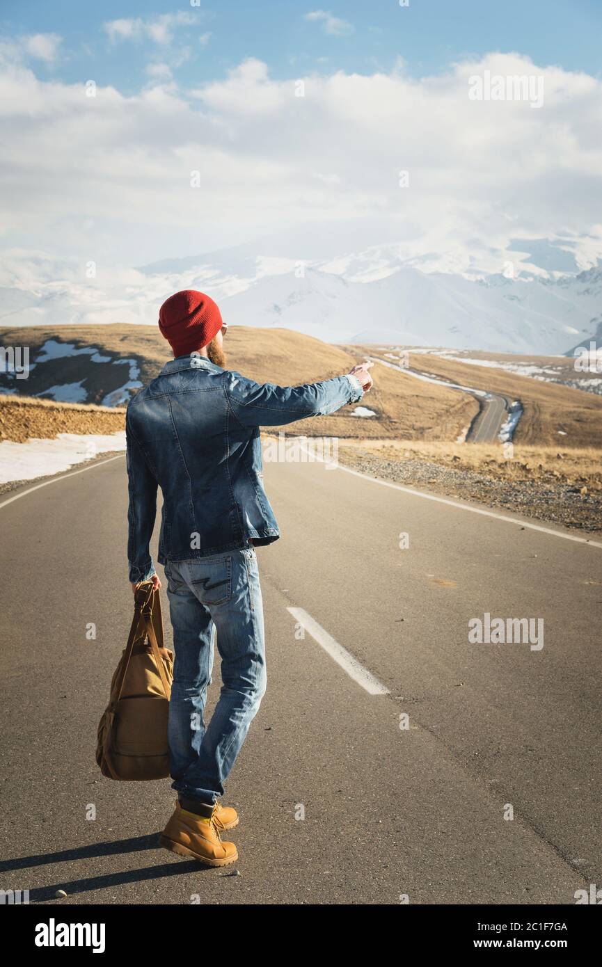 Concetto di turismo e di gente - Hipster elegante che cammina lungo la strada di campagna all'aperto e punta il dito a qualcosa Foto Stock
