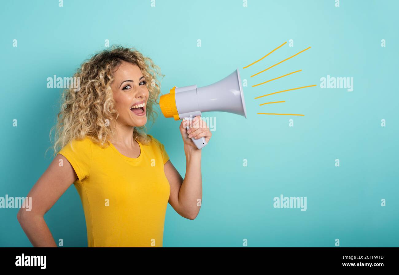 La donna parla con l'altoparlante. Espressione gioiosa. Sfondo ciano Foto Stock