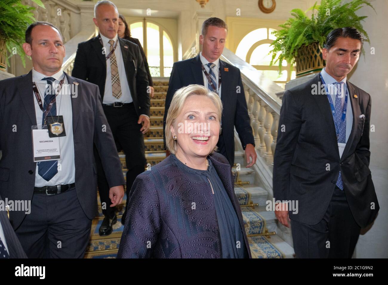 Italia, Como, 'Forum Ambrosetti' evento, HiIlary Clinton con abito blu sorrisi. Dietro le protezioni della carrozzeria Foto Stock