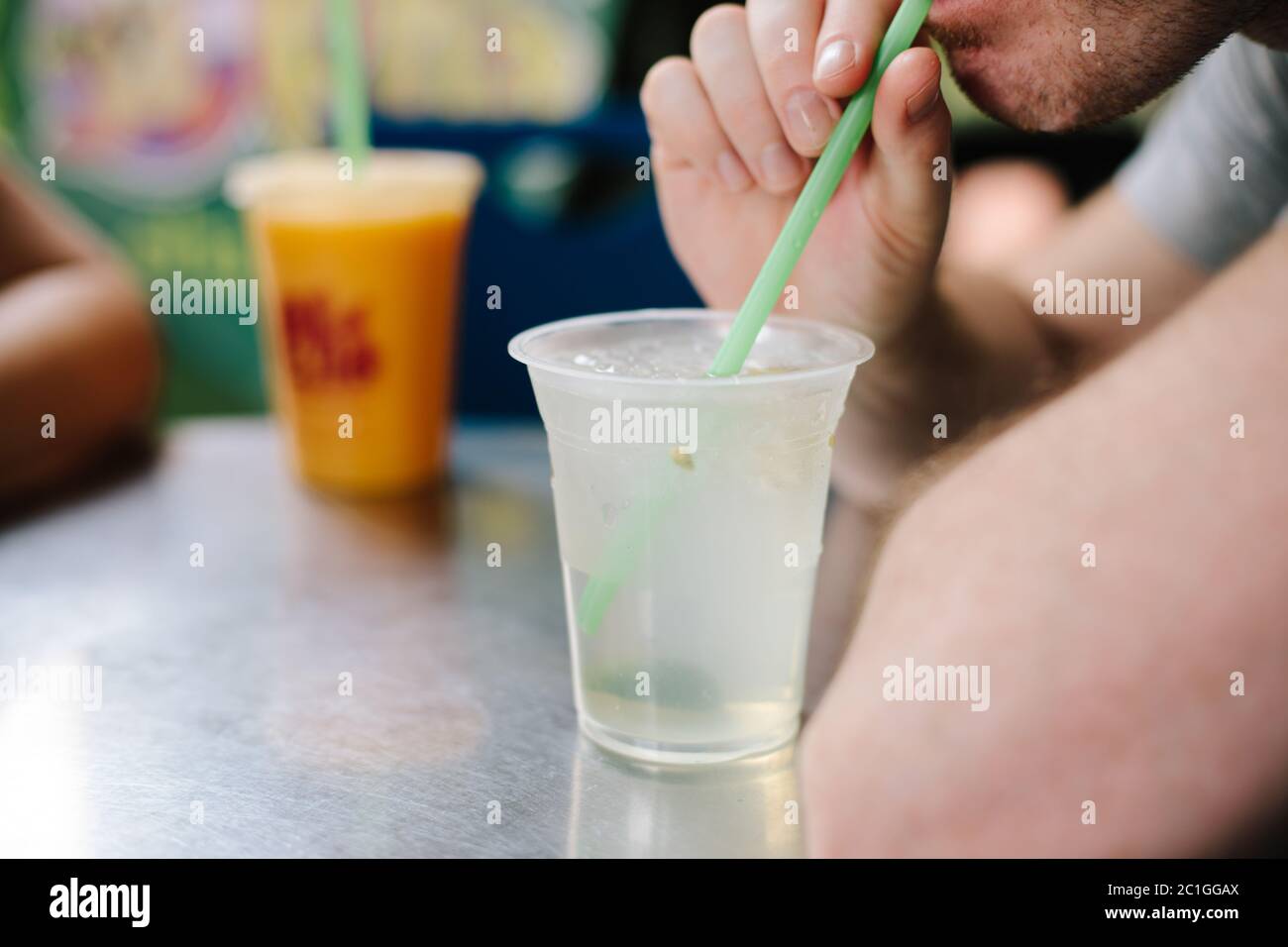 Un uomo che beve succo di lime fresco attraverso una paglia Foto Stock