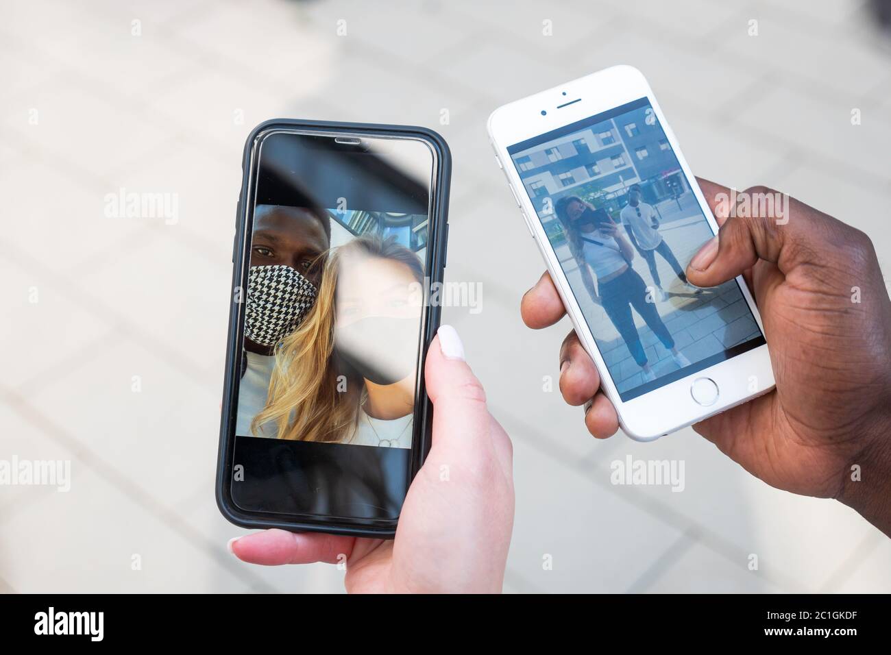 Giovane coppia mista di corse selfie su schermi telefonici. Solo mani. Vista ad angolo alto. Foto Stock