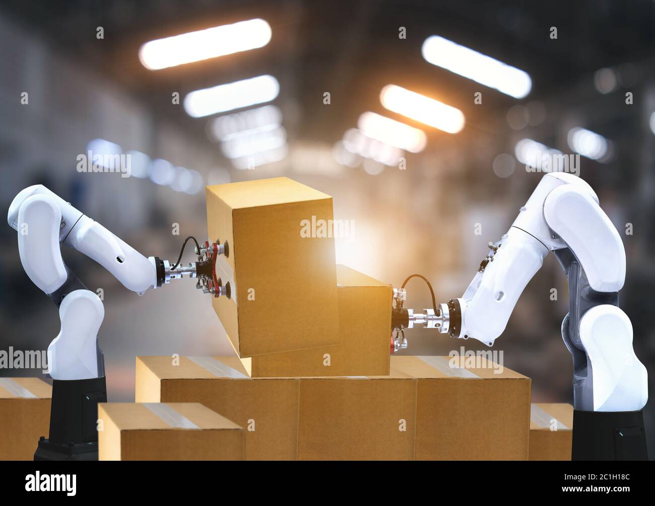 I bracci robotizzati trasportano scatole di cartone per l'imballaggio dell'industria di consegna Foto Stock