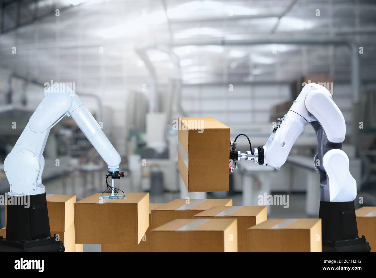 I bracci robotizzati trasportano scatole di cartone per l'imballaggio dell'industria di consegna Foto Stock