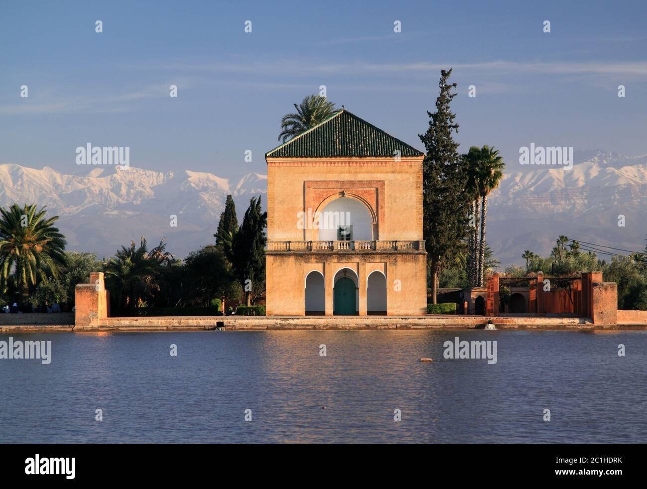 Marocco, Marrakech, Padiglione Menara si è riflesso sul suo lago nel sole del tardo pomeriggio. Montagne dell'Atlante innevate sullo sfondo. Foto Stock