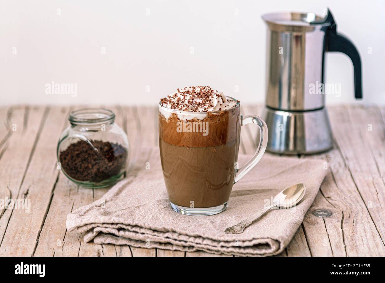 Caffè ghiacciato con panna montata e gocce di cioccolato su tavolo di legno, fuoco selettivo Foto Stock