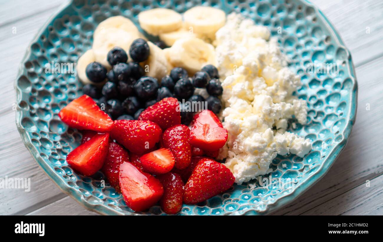 Piacere di mattina. Sana colazione estiva. Formaggio di cottage con frutti di bosco e miele. Colazione accogliente e facile Foto Stock