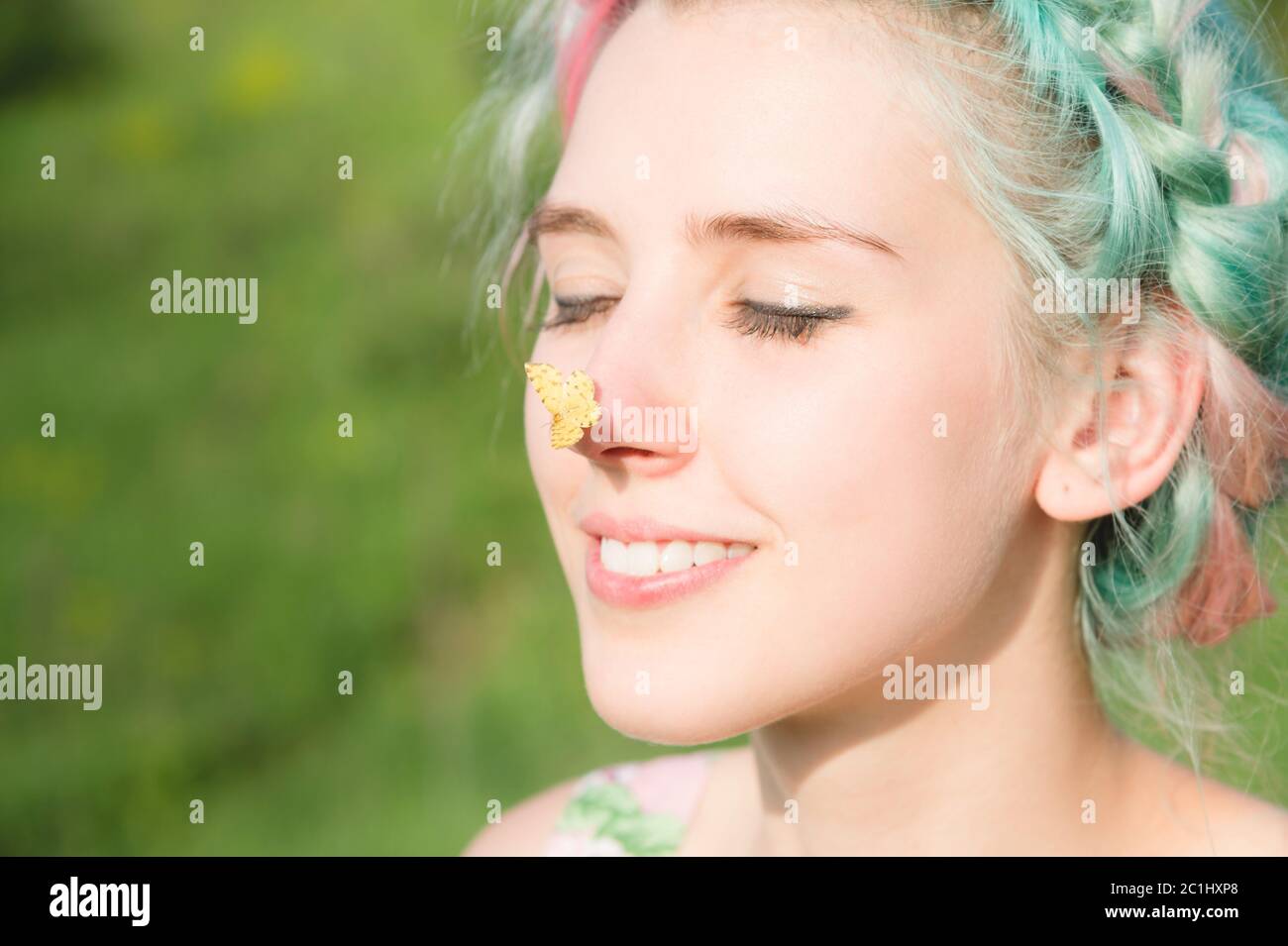 Farfalla gialla seduta sul naso cute giovane ragazza sulla natura. Armonia e godimento in natura Foto Stock