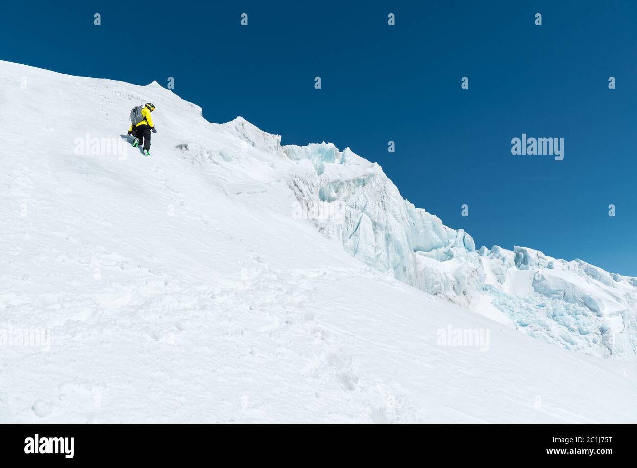 Uno sciatore in un casco e maschera con uno zaino si erge su un pendio sullo sfondo della neve e di un ghiacciaio. Freeride backcountry Foto Stock