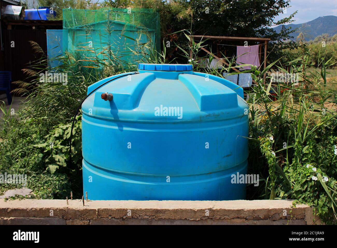 serbatoio di plastica blu grande vicino a casa in una regione arida. Insediamento nel territorio della Repubblica di Crimea Foto Stock