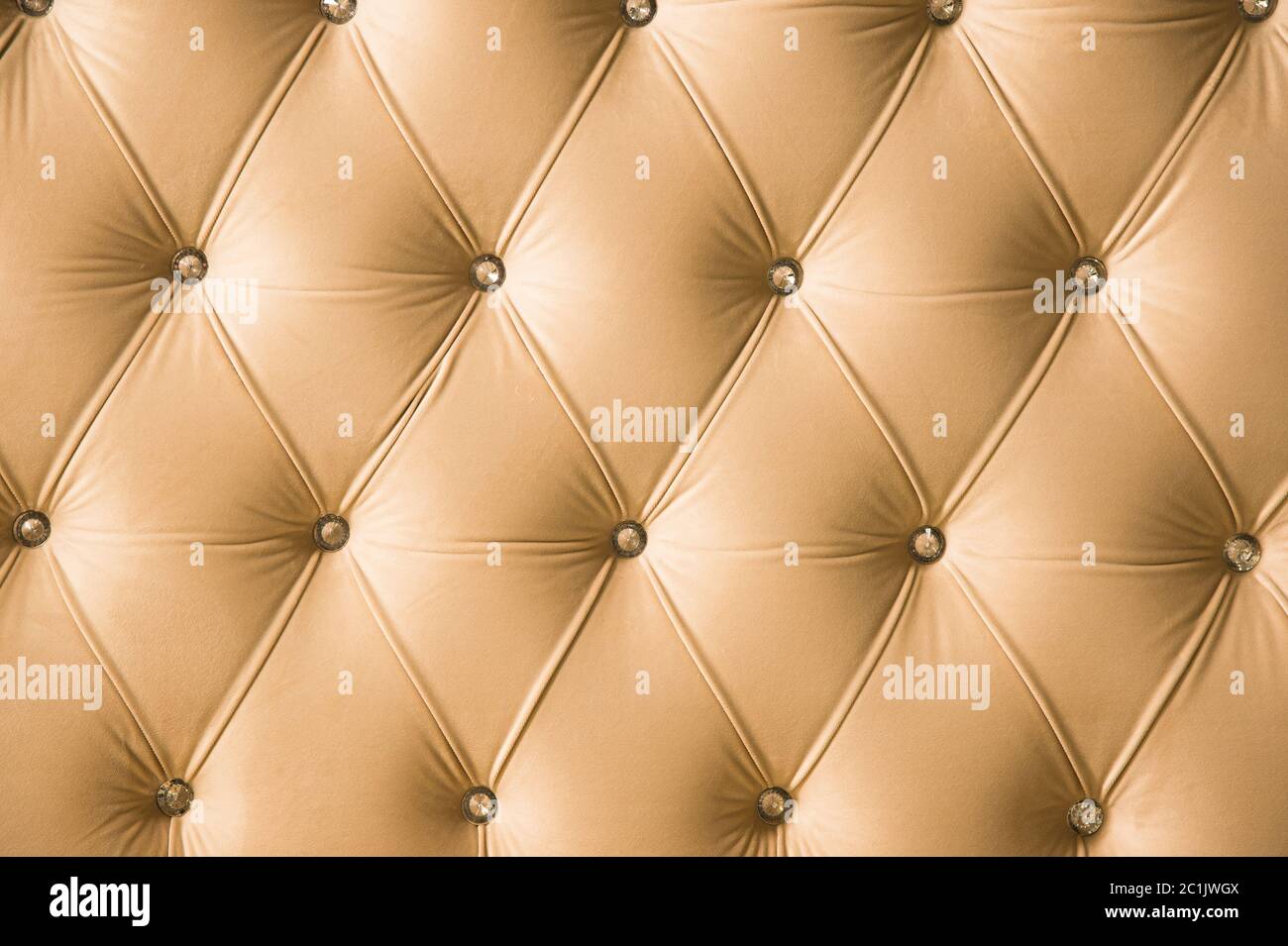 Fondo tessile beige morbido con bottoni simmetrici sugli angoli dei diamanti. Elementi di arredamento morbidi e costosi. Lusso Foto Stock