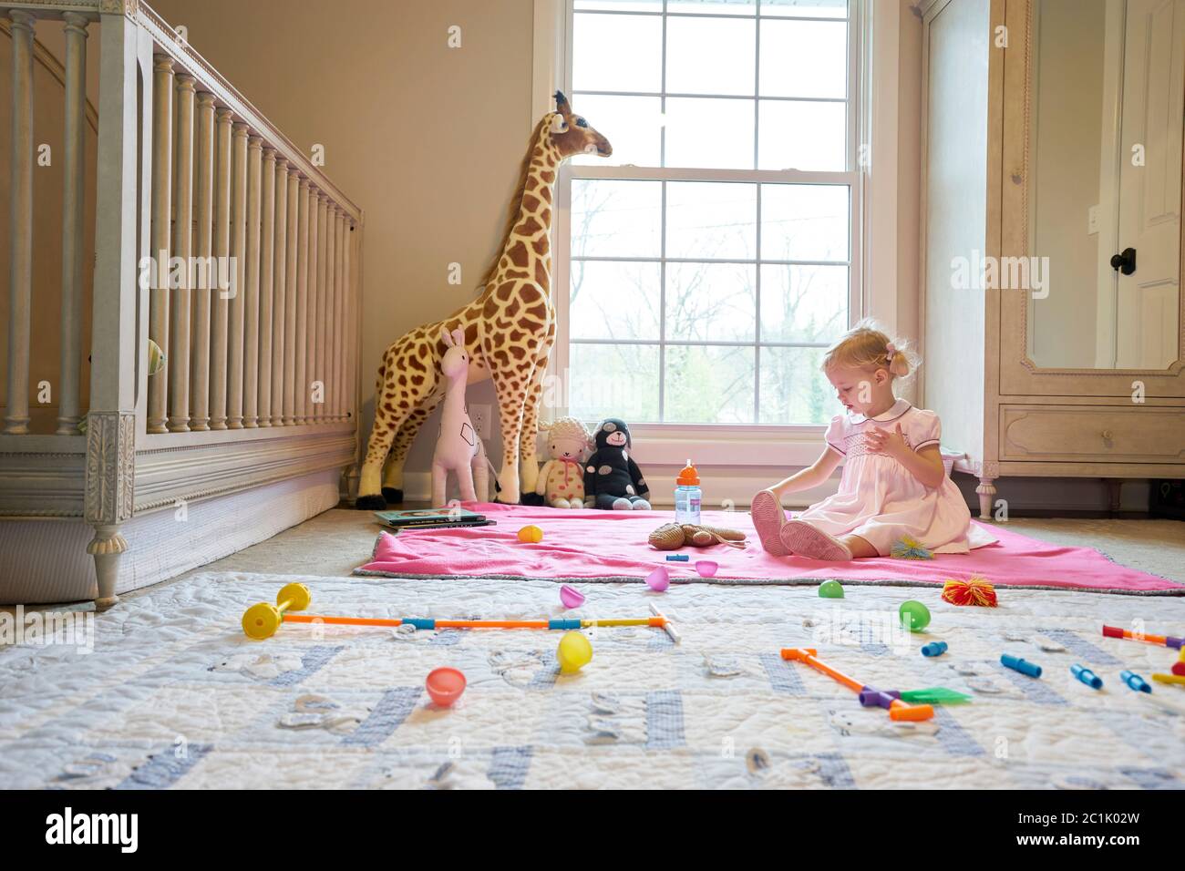 Una bambina gioca nella sua stanza da sola Foto Stock