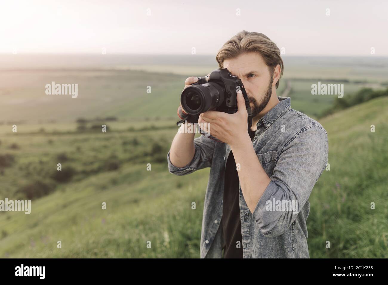 Fotografo di viaggio esperto che utilizza la fotocamera digitale in collina Foto Stock