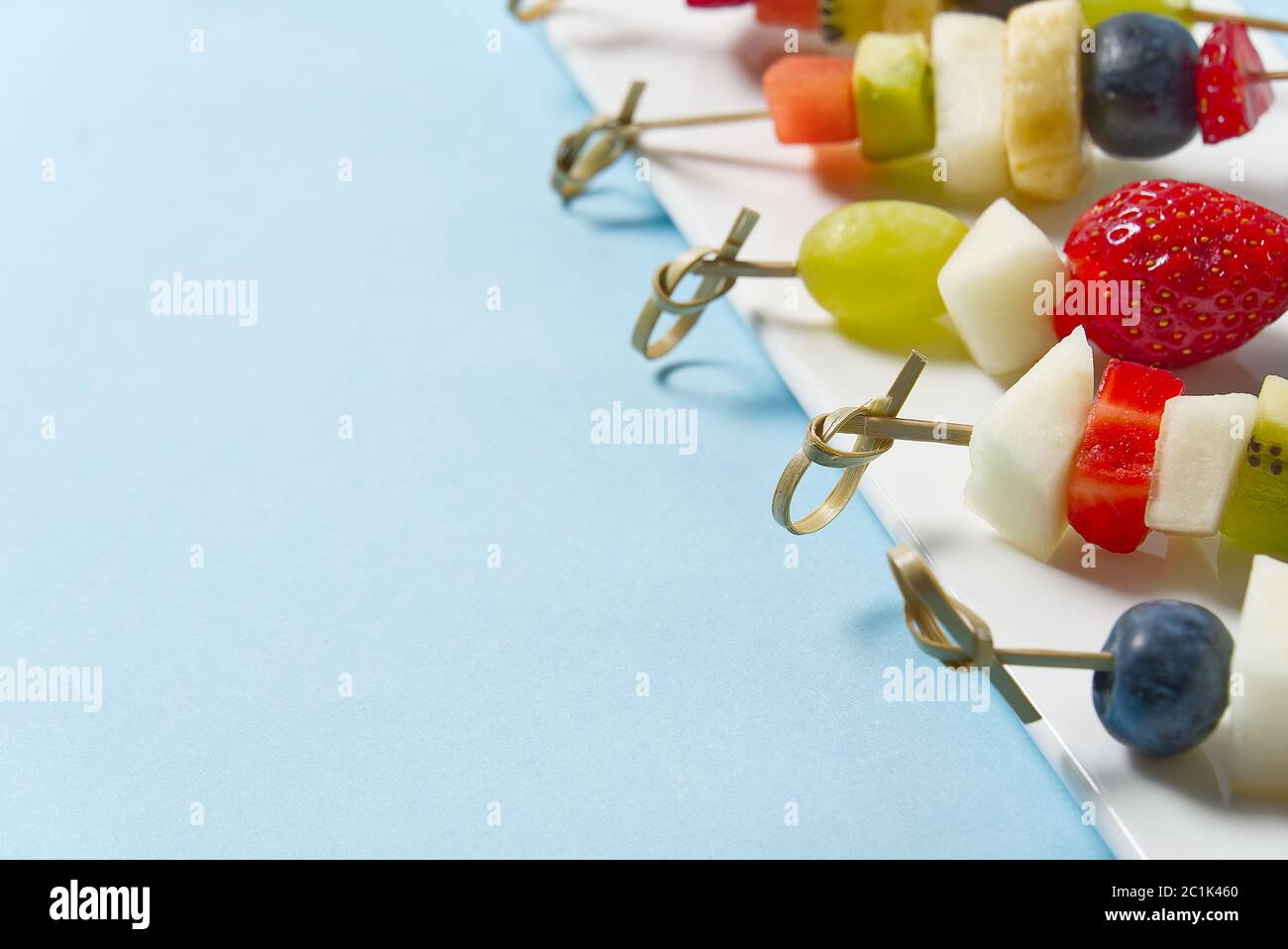 Crostini di frutta. Tartine di frutta fresca su piatto bianco. Frutta mista in piatto bianco stile alimentare sano, sfondi blu. Foto Stock