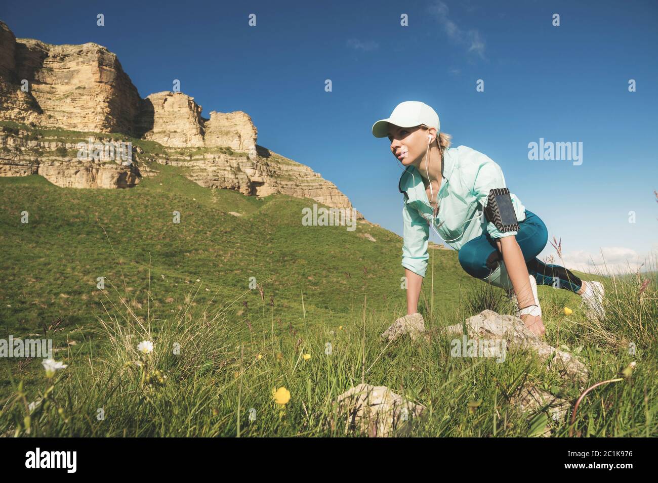 Donna atletica era pronta a correre ai piedi delle rocce. Il corridore di idoneità nella linea di partenza finita crea un'estate all'aperto Foto Stock