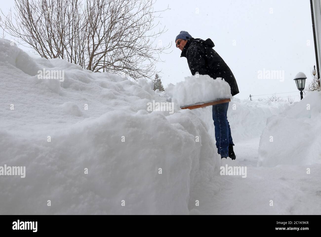 In inverno, un uomo tinge la neve da un marciapiede. Rimozione della neve durante la nevicata pesante in Germania Foto Stock