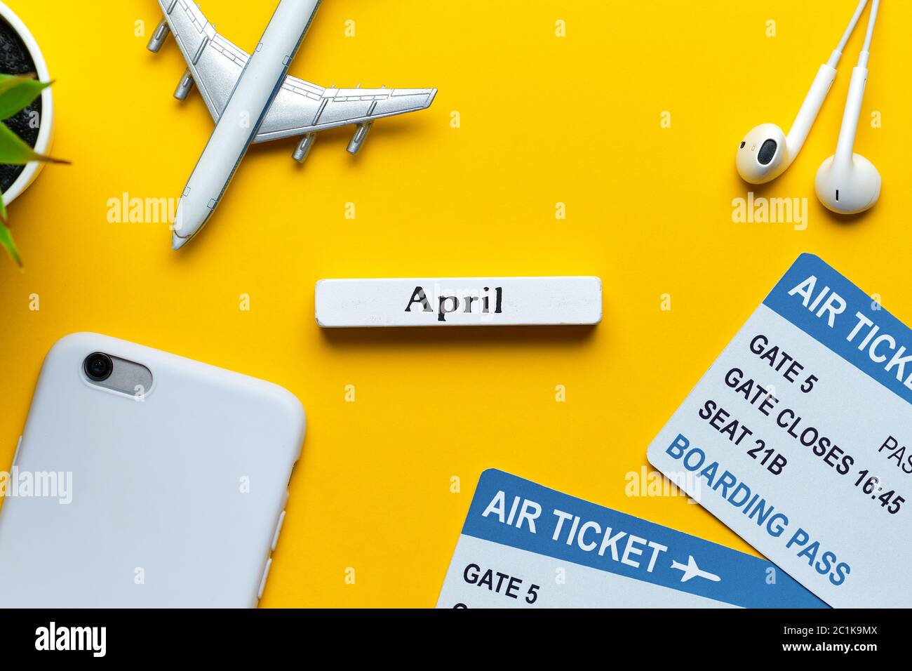 Concetto di vacanza di aprile con aereo e biglietti su uno sfondo giallo vista dall'alto Foto Stock