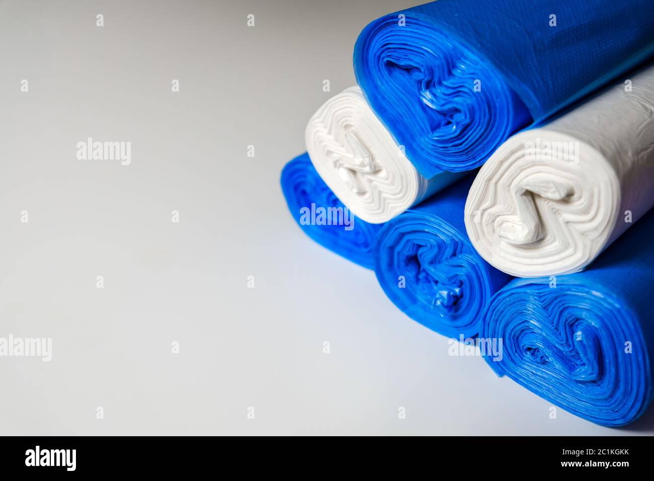 Mazzo di sacchetti di plastica blu su una superficie bianca. Materiali riciclabili per proteggere l'ambiente. Servizi di pulizia durante l'isolamento del coronavirus. Foto Stock