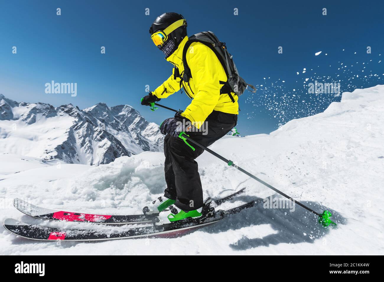 Sciatore professionista alla velocità prima di saltare dal ghiacciaio in inverno contro il cielo blu e le montagne Foto Stock