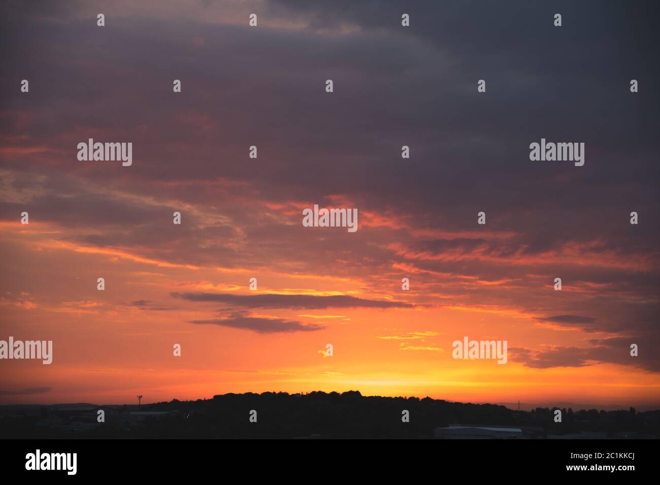Cielo serale dopo il tramonto con nuvole rosse e la sagoma del settore privato di una piccola città Foto Stock