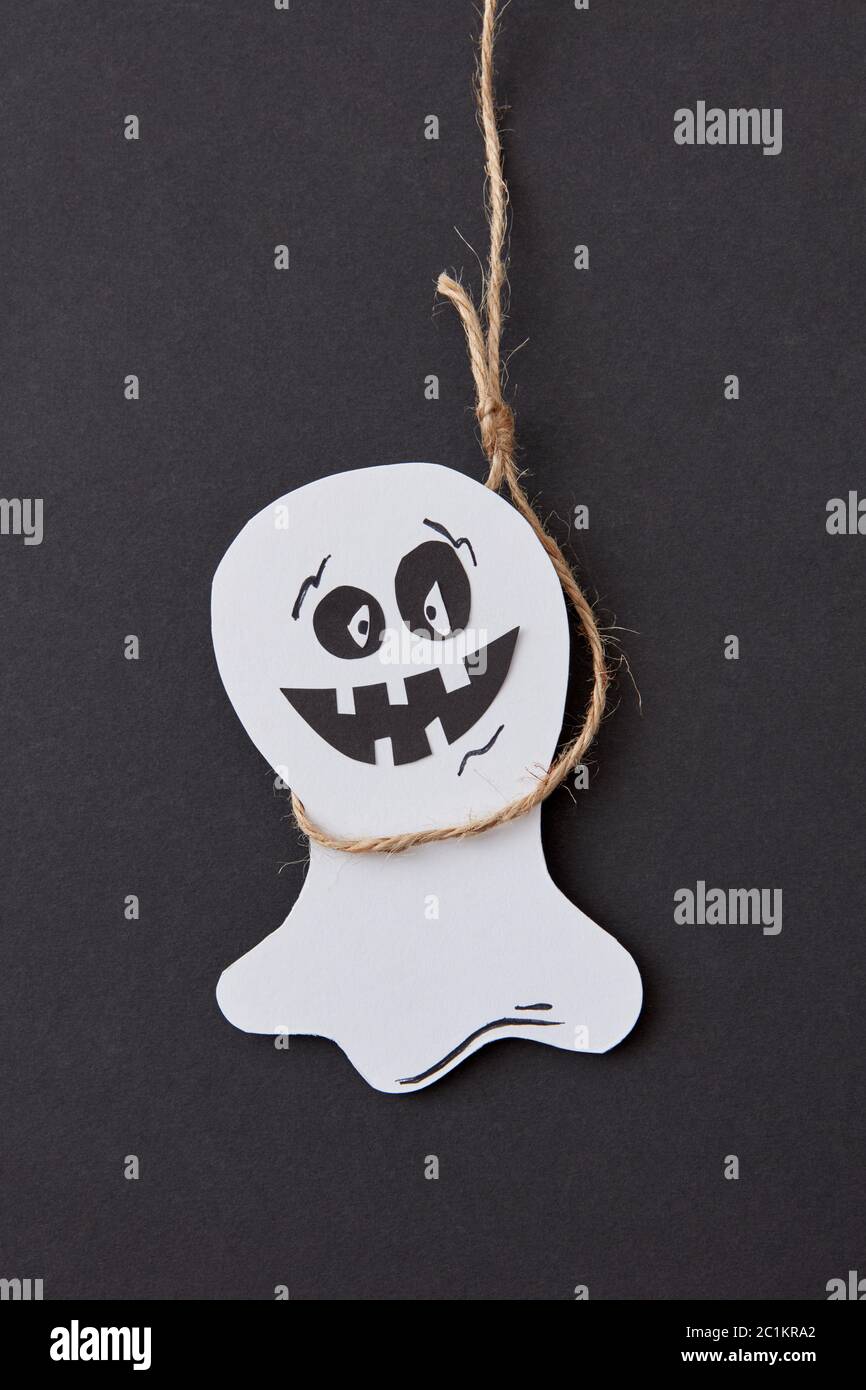 Halloween biglietto di auguri con ridere battenti scary Casper pendente da una corda fatti a mano da carta su un nero . Foto Stock