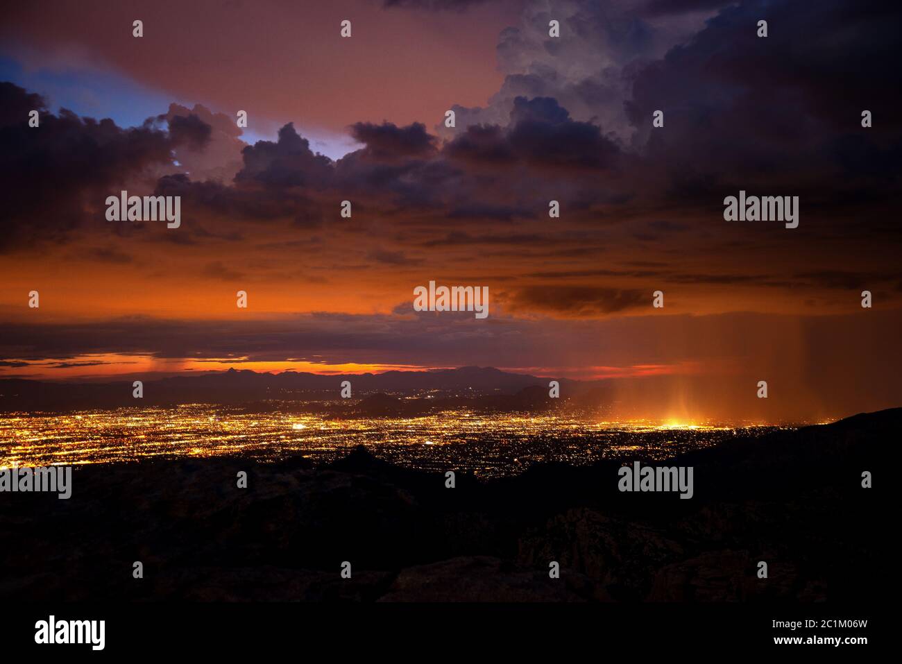 Le luci della città di Tucson si illuminano al tramonto durante una luna piena a settembre durante una squadra di monsoni a Windy Point, nelle montagne di Santa Catalina, Mo Foto Stock