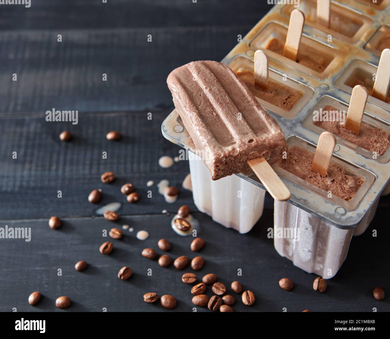 Il ghiaccio in plastica forma lecca stampi con la produzione fatta in casa di gelato al cioccolato e caramelle in stampi per ghiaccio su uno sfondo di legno Foto Stock