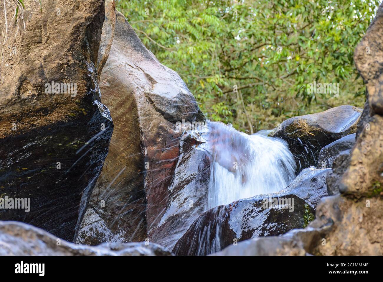 Piccola cascata con acque limpide che attraversano le rocce Foto Stock
