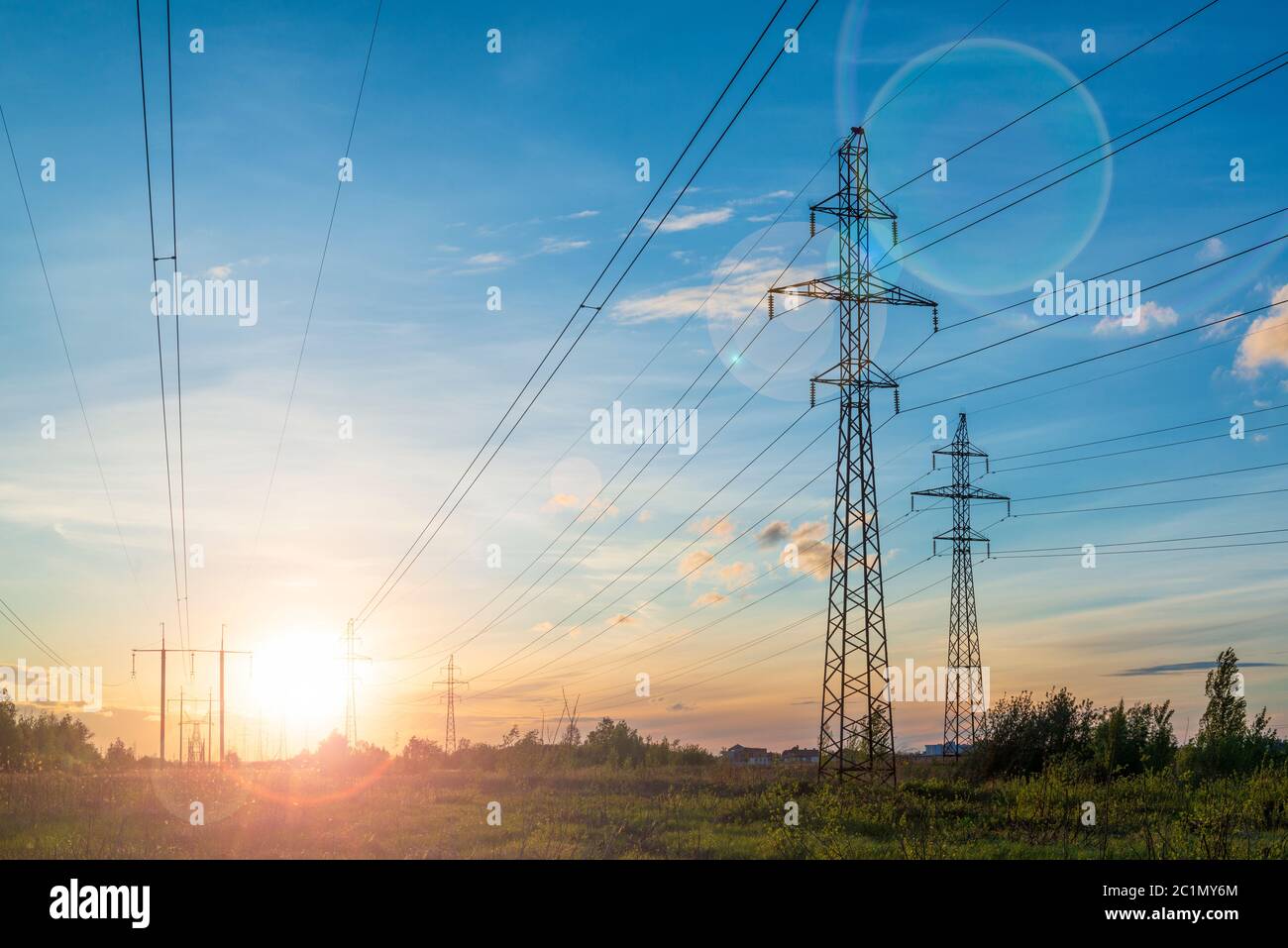 Linee elettriche multiple al tramonto con luce solare. Distribuzione dell'energia e ambiente Foto Stock