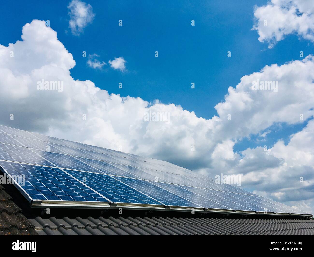 Energia alternativa verde solare, pannelli fotovoltaici sul tetto e cielo blu con nuvole Foto Stock