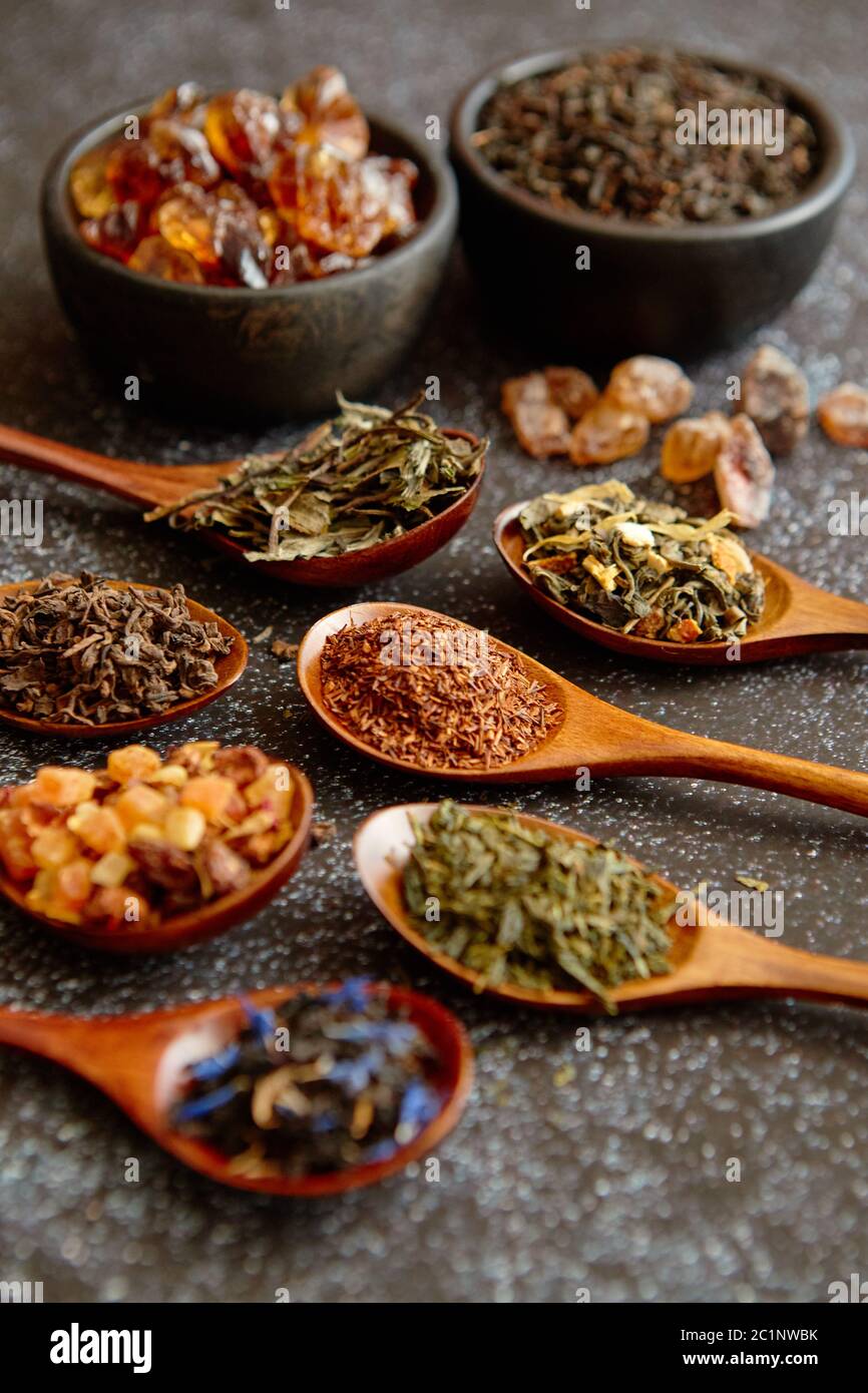 Cucchiai con diversi tipi di estratto secco di foglie di tè. Foto Stock