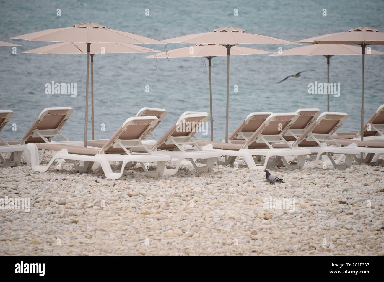 Sedie a sdraio e grandi, piccole, pietre rotonde sul Mediterraneo nella provincia di Alicante, Spagna Foto Stock