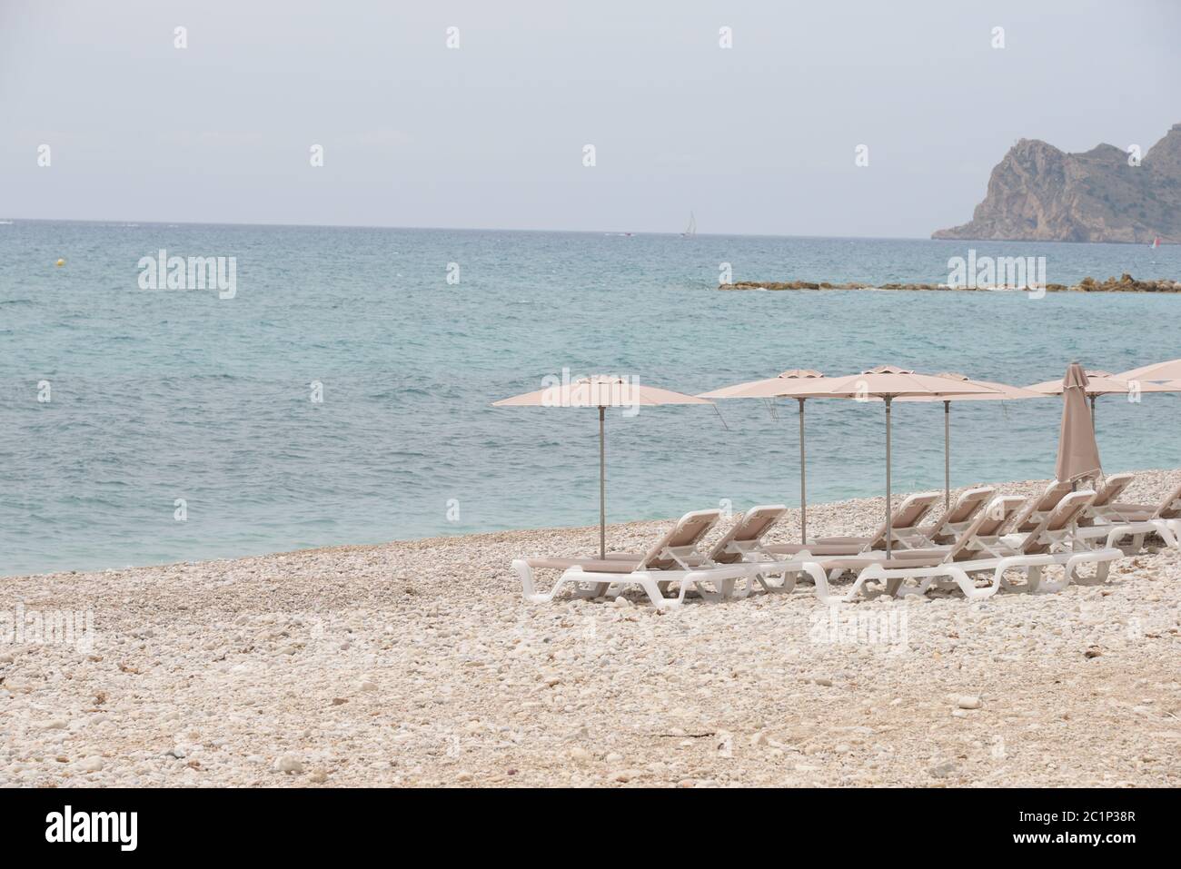 Sedie a sdraio e grandi, piccole, pietre rotonde sul Mediterraneo nella provincia di Alicante, Spagna Foto Stock