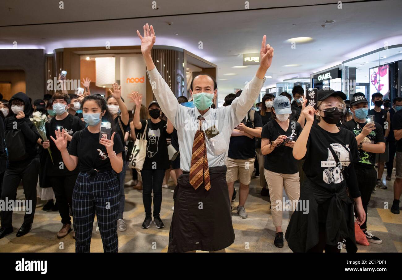 HONG KONG, HONG KONG SAR, CINA: 15 GIUGNO 2020. I manifestanti tengono in mano il cartello "5 richieste non una in meno" nel Pacific Place Mall di Admiralty Hong Kong. Sono lì per commemorare la prima morte dei manifestanti democratici di un anno fa. Marco Leung cadde alla sua morte per ponteggi fuori dall'edificio il 15 giugno 2019. Divenne noto come l'uomo dell'impermeabile. Immagine d'archivio Alamy/Jayne Russell Foto Stock