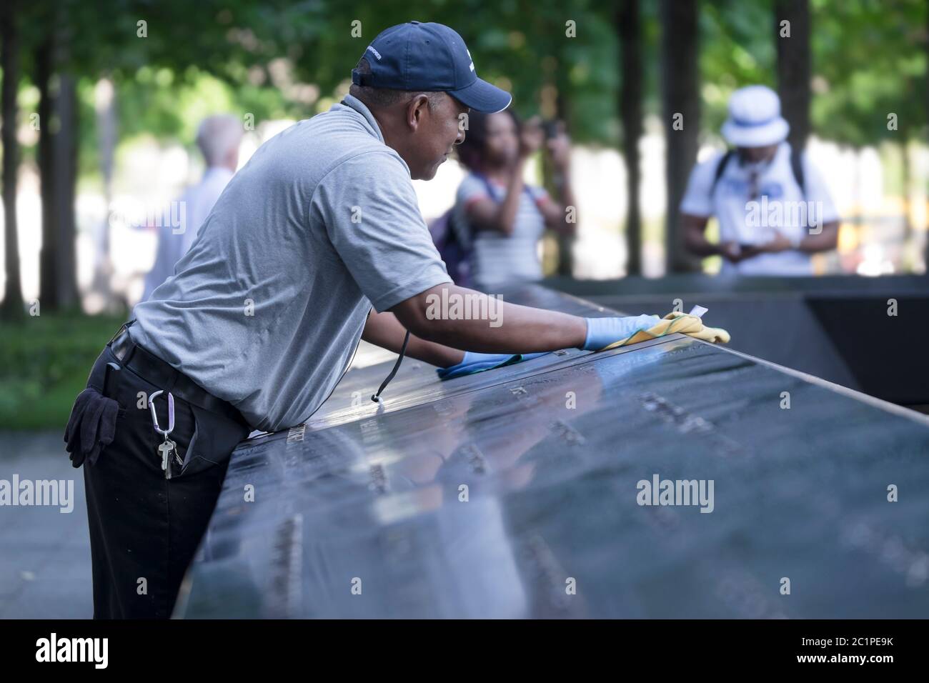 L'uomo pulisce la lastra di granito con i nomi delle persone che sono morte negli attacchi di New York al Ground Zero Memorial a Manhattan Foto Stock