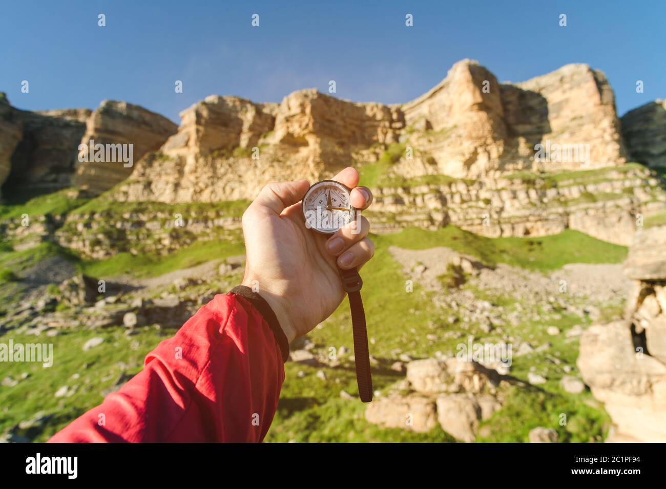 Uomo alla ricerca di direzione con una bussola in mano nel punto di vista estivo delle montagne. Ricerca direzione Foto Stock