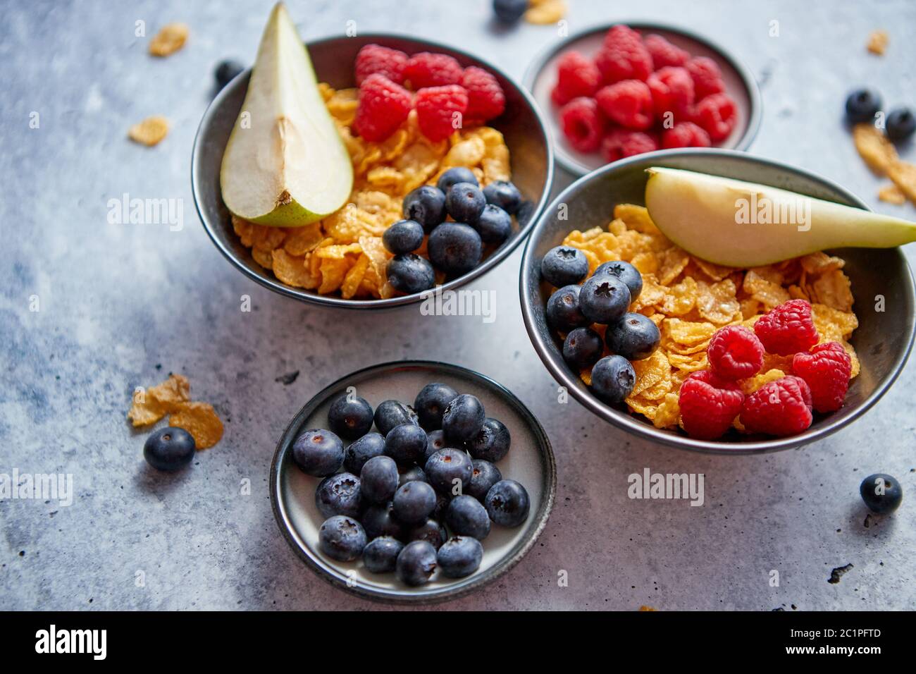 Golden corn flakes con frutti freschi di lamponi mirtilli e pera in vaso in ceramica Foto Stock