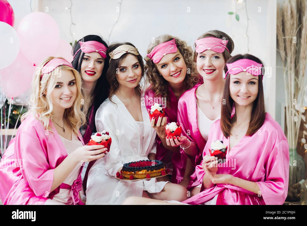 Belle ragazze in rosa le vesti e le maschere di sospensione con il dessert a docce nuziale. Foto Stock