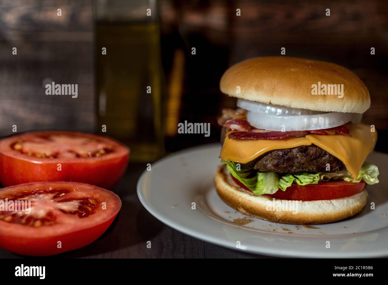 Panino con hamburger e pomodori in background in legno Foto Stock