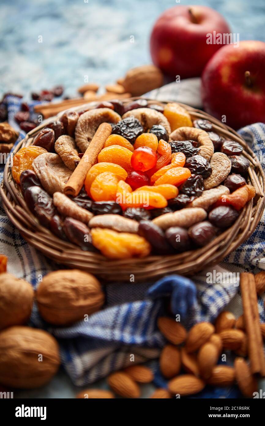Composizione di frutta secca e noci in piccolo vaso in vimini collocato sul tavolo di pietra Foto Stock