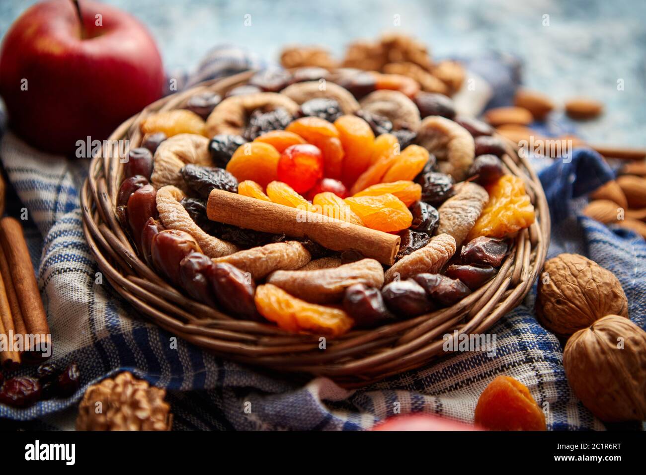 Composizione di frutta secca e noci in piccolo vaso in vimini collocato sul tavolo di pietra Foto Stock