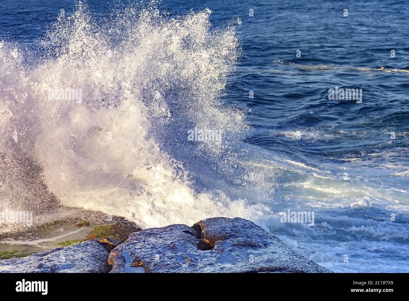 Onde che si schiantano contro rocce con spray Foto Stock