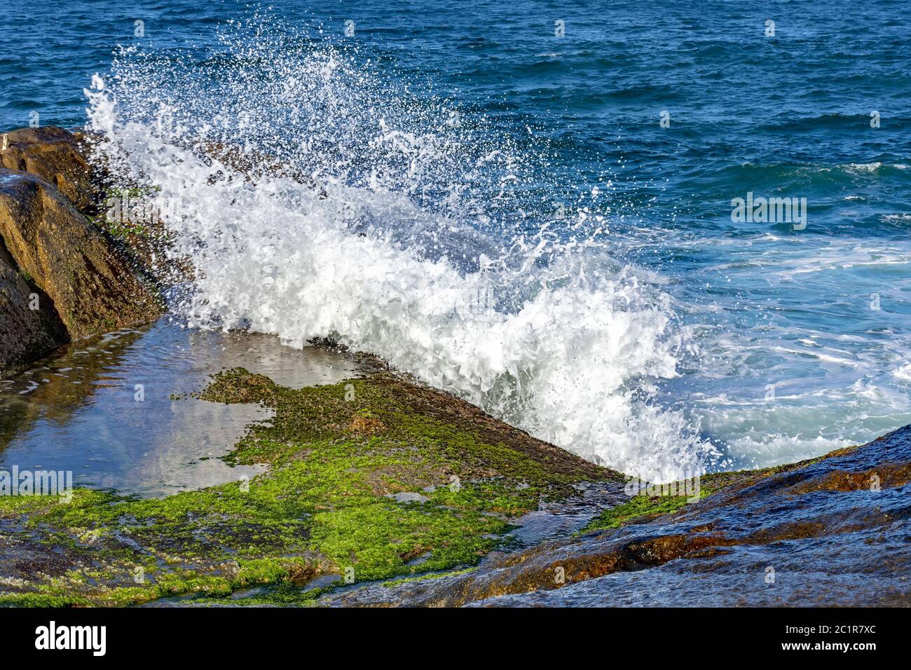 Onde che si infrangono su rocce con acqua nebulizzata Foto Stock