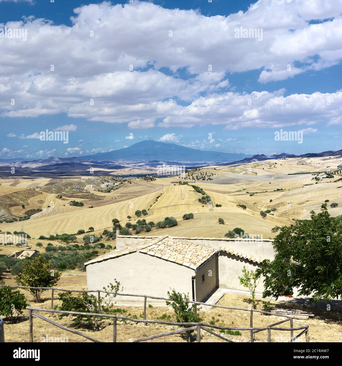 Paesaggio Sicilia estate di campagna intorno all'Etna con casa rurale, campo di grano e ulivi sotto il paesaggio nuvoloso Foto Stock